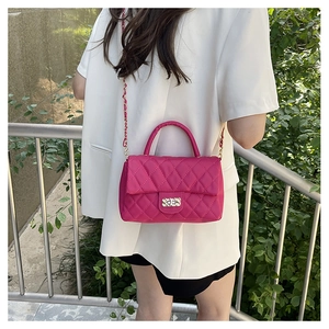 Close-up of pink quilted crossbody bag with gold chain strap on a white blazer model
