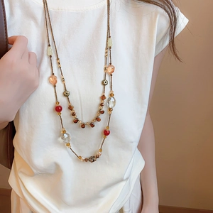 Detail of vintage bohemian double-layer beaded necklace with red and amber floral charms