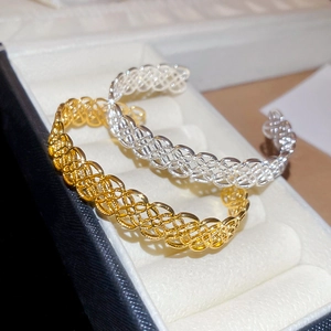 Détail des bracelets tissés dorés et argentés placés dans un écrin à bijoux blanc