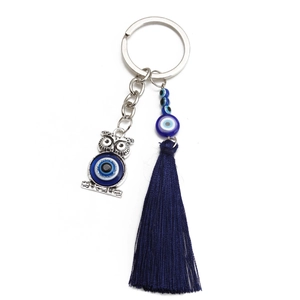 Detail view of owl keychain with blue evil eye charm and silky tassel pendant