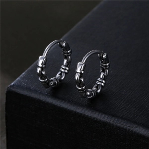 Vintage stainless steel huggie earrings with a woven chain texture on a black box