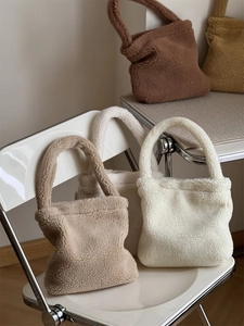 Detailed texture of fuzzy lamb wool tote bags in various warm earthy tones on a chair