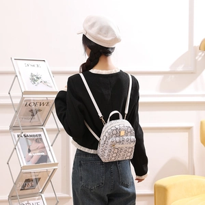 Detailed view of snake skin pattern mini backpack with gold zippers and white straps