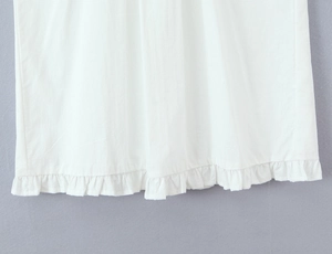 Détail de l'ourlet de robe blanche avec plis à volants délicats et texture coton et lin