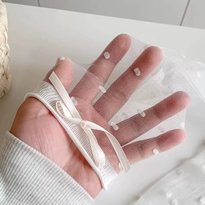 Détail de chaussettes en résille blanche à pois avec un nœud en soie sur la main