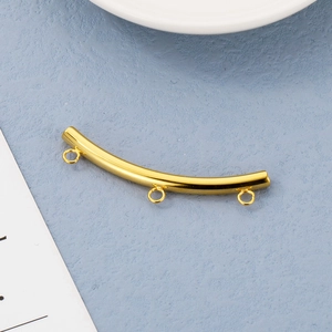 Detailed view of a curved stainless steel gold tube with three small hanging loops