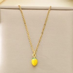 Close-up of golden necklace featuring a vibrant yellow lemon pendant with green enamel leaves