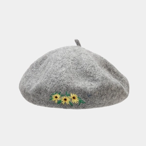 Nahaufnahme der gelben Gänseblümchen-Stickerei auf einer dunkelgrauen Wollbaskenmütze