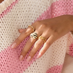 Detailed view of three-piece gold heart ring set with rhinestones and zebra enamel