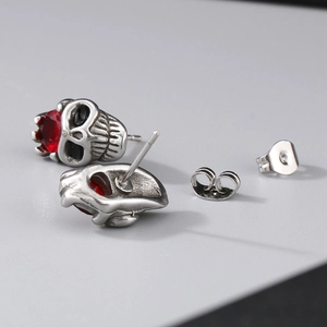 Macro shot of punk skull stud earrings with red crystals and vintage silver finish