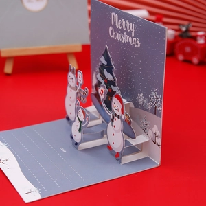 3D pop-up Christmas card featuring snowman and tree on a festive red background