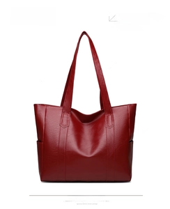 Detail view of deep red tote bag showing faux leather texture and side pocket design