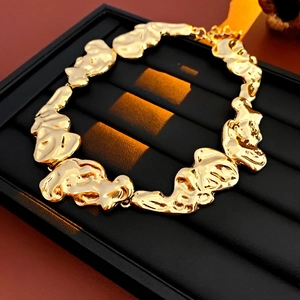 Close-up of golden irregular textured lava metal necklace on black jewelry tray