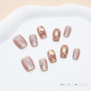 Detail of pink press-on nails with cat eye finish, butterfly charms and plaid patterns