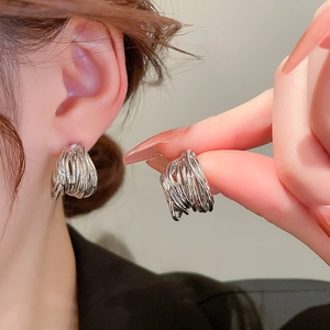 Silver multi-layered geometric C-shape hoop earrings worn by a model in close-up shot