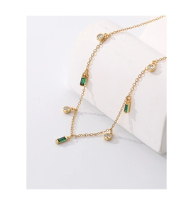 Detail of gold geometric necklace featuring emerald and white zircon square gemstones