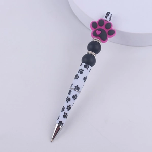 Detail of DIY beaded pen featuring pink silicone paw bead and rhinestone spacers