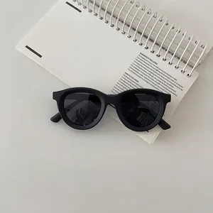 Flat lay of black round silicone sunglasses on a white notebook for kids' fashion
