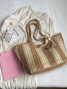 Vertical striped straw tote bag with tassels and woven handles for summer beach vacations