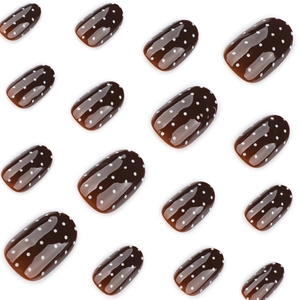 Brown amber press-on nails with white polka dots in a glossy round short oval shape