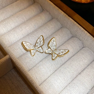 Detailed macro view of butterfly stud earrings with gold plating and white enamel wings