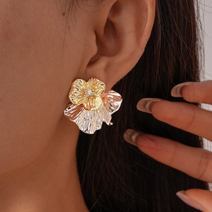 Detailansicht zweifarbiger Metall-Blumenohrringe mit Zirkonia und Faltenstruktur am Ohr