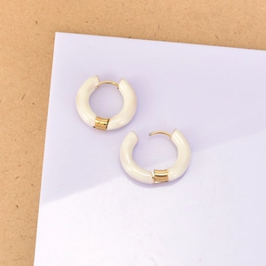 Détail de créoles en émail ivoire avec placage en or 18 carats sur support violet