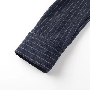 Dettaglio del polsino della camicia grigio scuro a righe che mostra la trama del tessuto