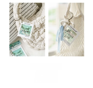 Transparent acrylic charm with star-shaped clasp and blue ribbon on a white textured bag