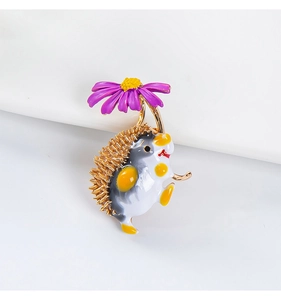 Macro detail of cartoon hedgehog brooch with purple flower and golden metal accents