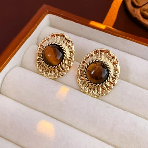 Détail de boucles d'oreilles vintage dorées avec bords martelés et pierre œil de tigre