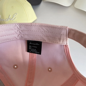 Détail de l'intérieur d'une casquette rose en coton avec étiquette et taille