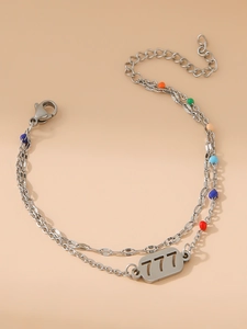 Dettaglio di un bracciale a doppio strato in acciaio inox con perline e ciondolo numero 777