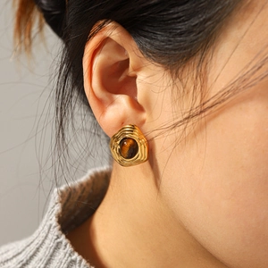 Close-up of vintage gold ripple texture earrings with tiger eye stone on model
