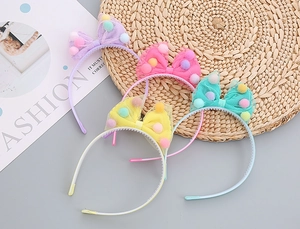 Detail showing set of 4 macaron colored girls headbands with mesh bow and colorful pom-poms