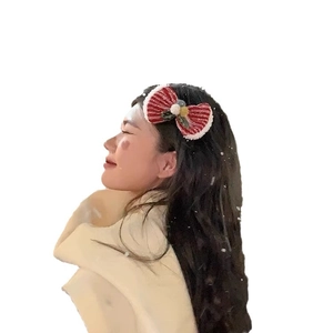 Red and white plush Christmas bow headband for women shown on model profile view