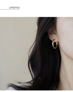 Lifestyle shot of a model wearing minimalist gold circular hoop earrings in 925 silver