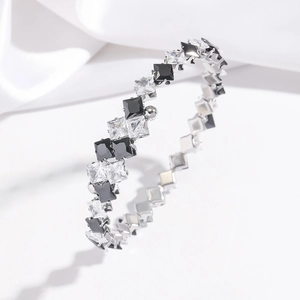 Macro shot of silver-tone steel bangle featuring black and white square-cut cubic zirconia