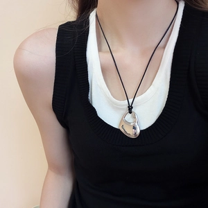 Close-up of model wearing an abstract silver heart pendant with black cord necklace