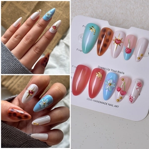 Detail of 3D cherry and floral almond fake nails set shown on model and display card