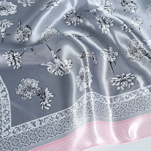 Detail of blue floral silk-like scarf featuring soft texture and pink geometric border