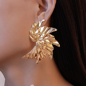 Detail of high-polished golden leaf-shaped earrings showing premium metallic texture