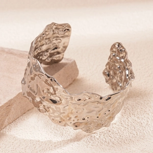 Detailed macro view of gold-tone wide cuff bracelet with irregular hammered texture