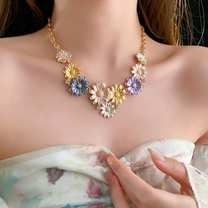 Detail of a gold necklace featuring colorful enamel daisies with sparkling crystal centers