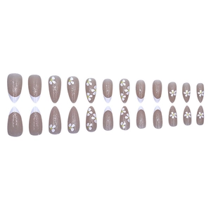 Détail macro de 24 faux ongles amande avec pointes françaises blanches et paillettes florales