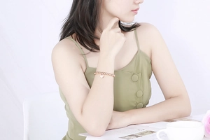 Rose gold beaded bracelet with heart charm worn on wrist in an elegant lifestyle setting
