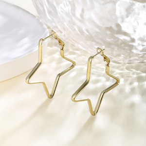 Macro shot of gold star-shaped hoop earrings on a decorative white porcelain background