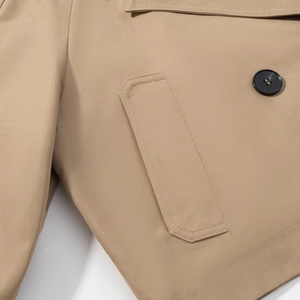 Close-up of khaki twill trench coat featuring a pocket and single-breasted button detail