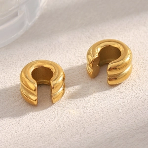 Macro shot of 18K gold plated double layer stainless steel ear cuffs on a textured surface