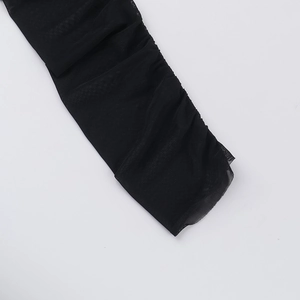 Détail de manche en tulle noir avec texture froncée et finition semi-transparente